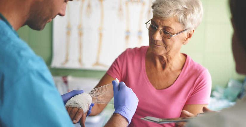 Woman receiving would care treatment to her left hand